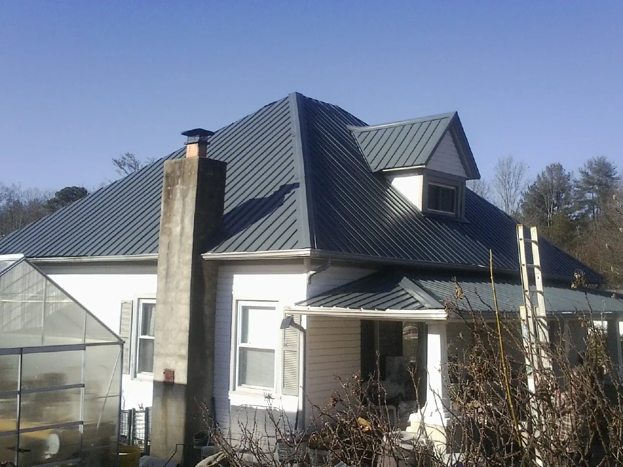 Dark blue standing seam metal roof on a white farmhouse with dormer — Slate & Tile Roof Repair by Roofing Brothers in Stockertown