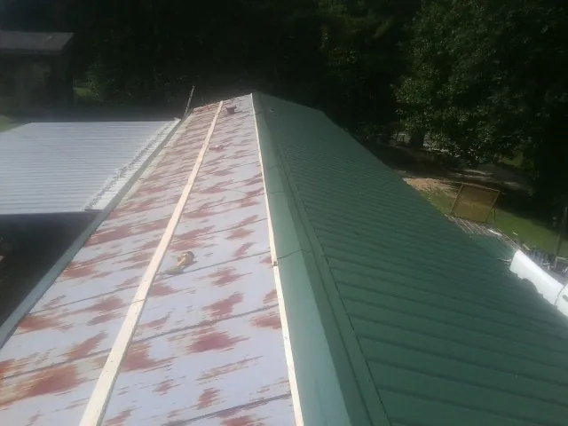 Old rusted panels beside newly installed green metal roofing — Wind Damage Roof Repair by Roofing Brothers in Stockertown