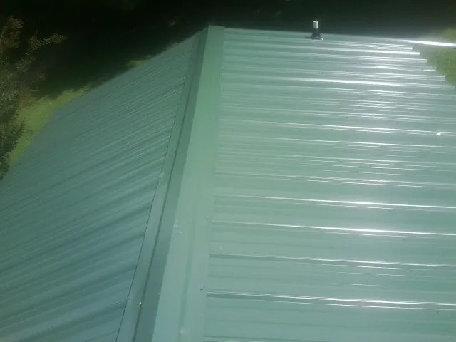 New green metal panels meeting at the ridge of a roof — Flat Roof Repair work by our crew in Stockertown