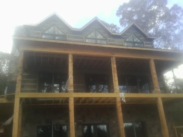 Dormers and porch framing on a large log home under construction — Roof Coating work by our crew in Stockertown
