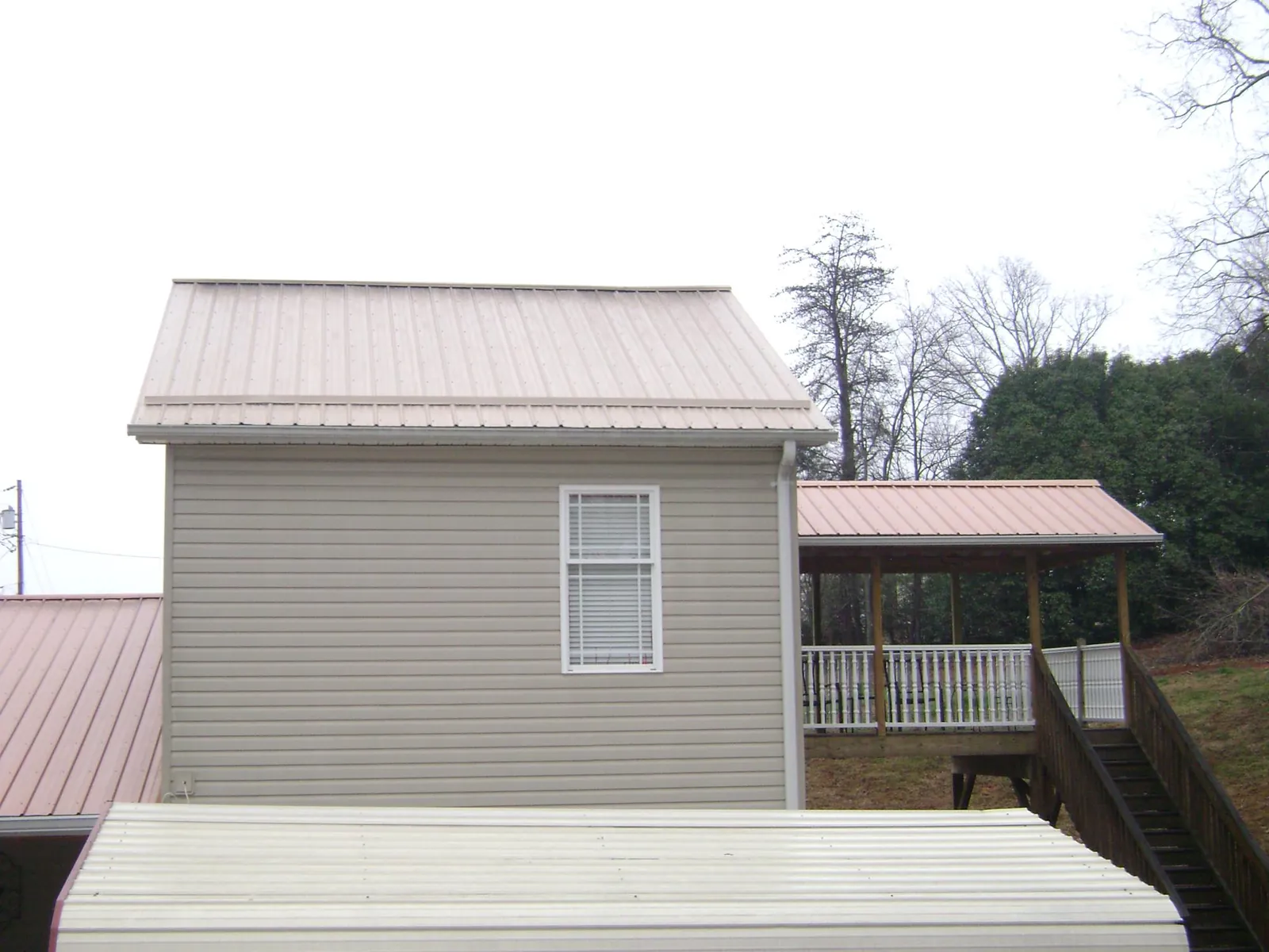 Tan metal roofs on a two story addition and attached porch, from a Roof Replacement job in Stockertown
