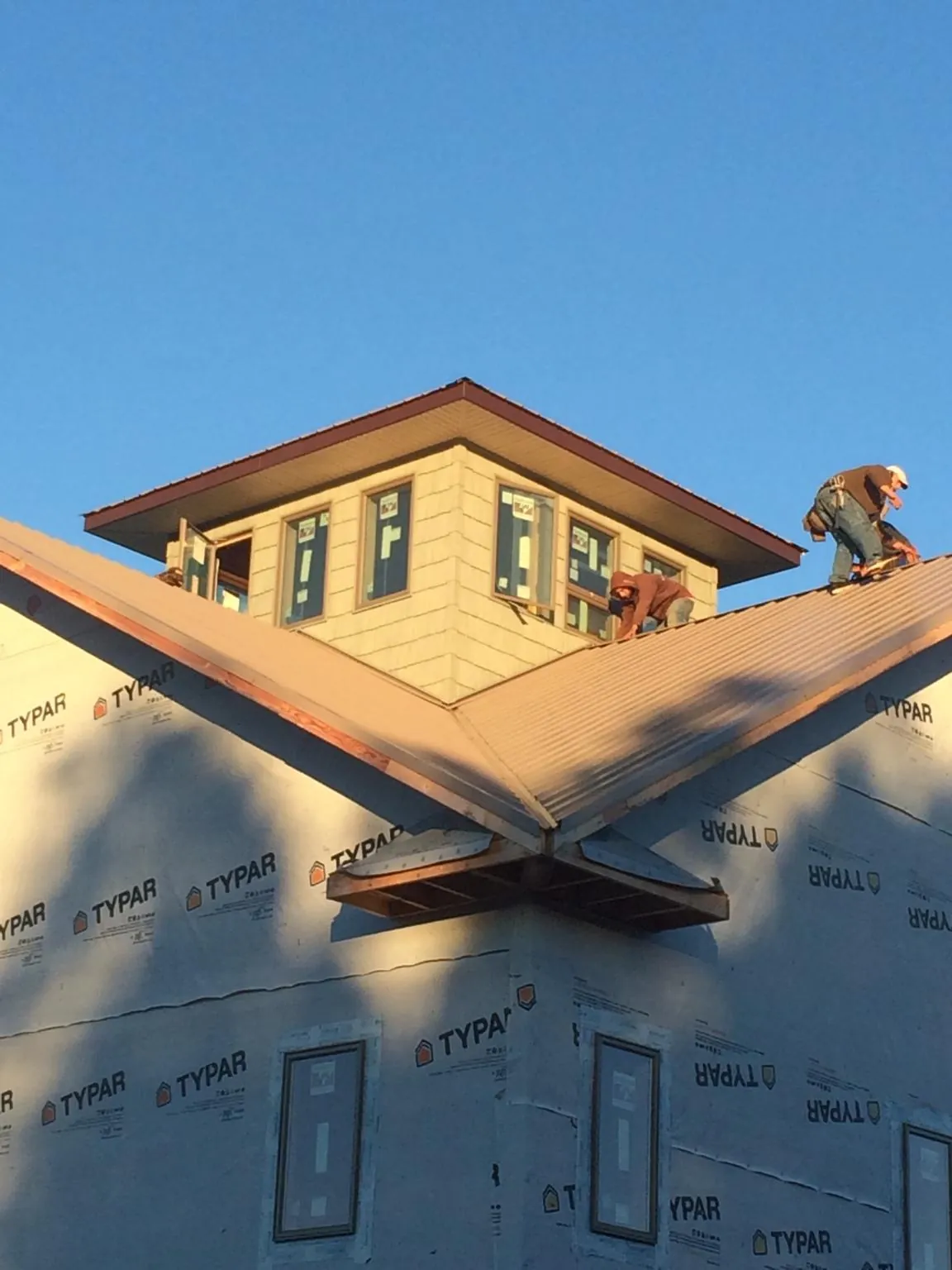 Roofers working around a rooftop cupola on a new metal roof at sunset — Roof Waterproofing in Stockertown by Roofing Brothers